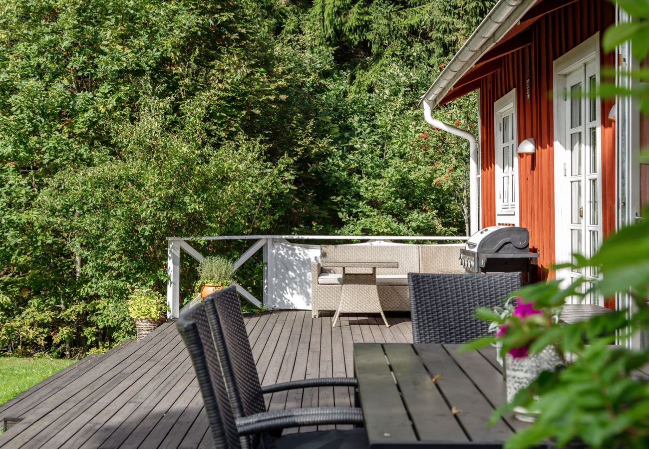 Röd stuga i Småland med stor terrass, grill och trädgårdsmöbler